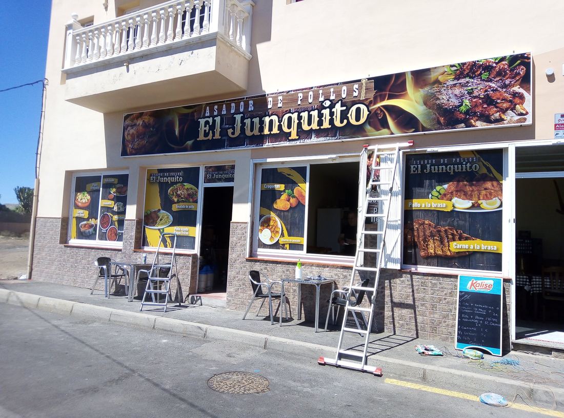 Fachada del asador El Junquito con rótulo y vinilos en las ventanas